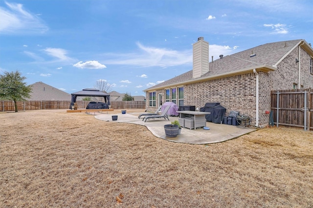 back of property with a gazebo, a patio area, and a lawn