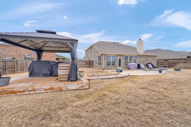 back of house featuring a gazebo, a wooden deck, a patio area, and a lawn