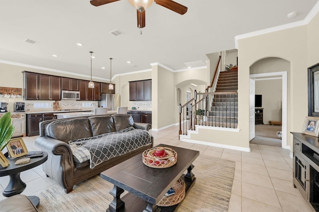 living room with crown molding, light tile patterned floors, and ceiling fan