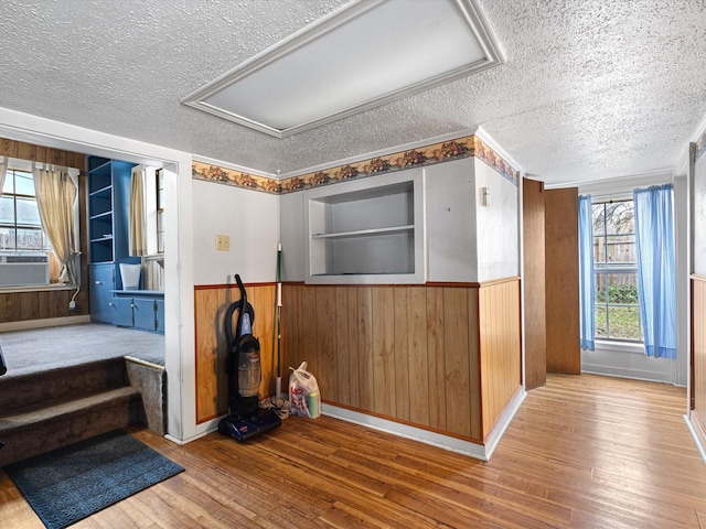 interior space featuring cooling unit, hardwood / wood-style floors, a textured ceiling, and wood walls