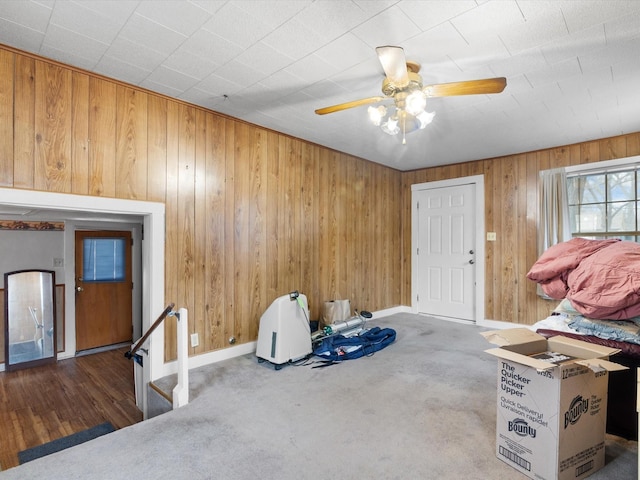 interior space with ceiling fan and wood walls