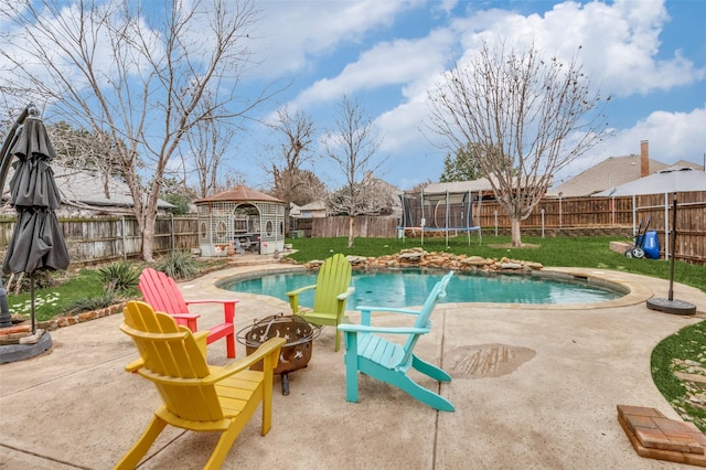 view of pool with a gazebo, a trampoline, a lawn, an outdoor fire pit, and a patio