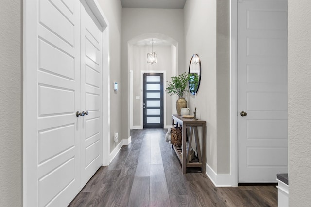 corridor with baseboards, arched walkways, and wood finished floors