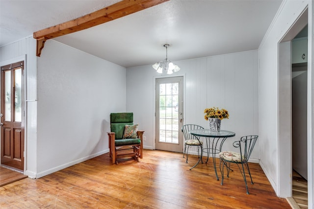 living area featuring beam ceiling, light hardwood / wood-style floors, and a notable chandelier