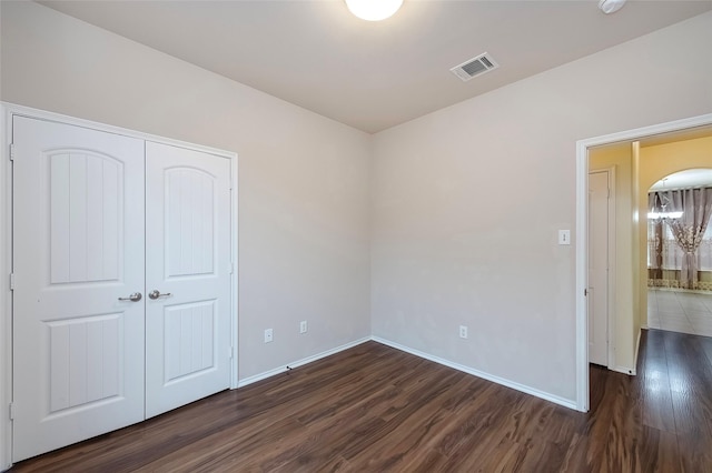 unfurnished bedroom featuring dark wood-type flooring and a closet