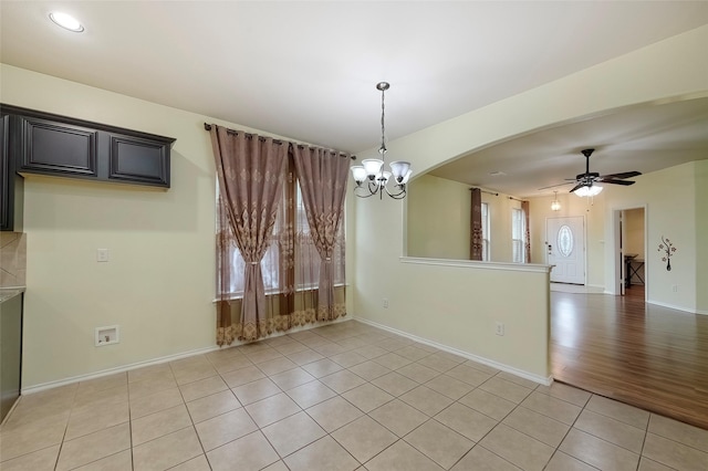 unfurnished dining area with ceiling fan with notable chandelier and light tile patterned floors