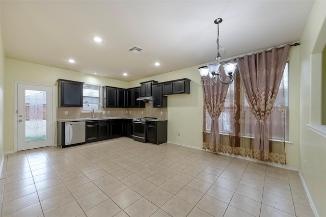 kitchen with light tile patterned flooring, tasteful backsplash, sink, stainless steel appliances, and an inviting chandelier