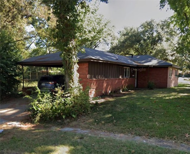 view of side of property with a yard, a carport, and brick siding