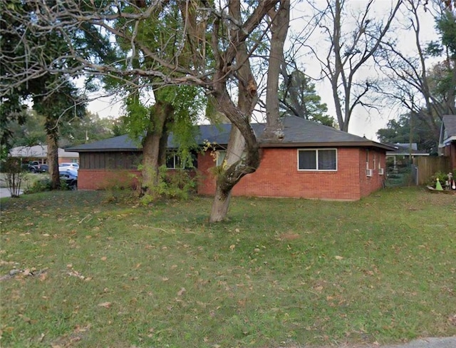 view of side of home with brick siding and a yard