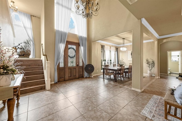 foyer with a high ceiling, light tile patterned flooring, a chandelier, and crown molding