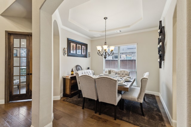 dining space featuring visible vents, a tray ceiling, arched walkways, hardwood / wood-style flooring, and a notable chandelier