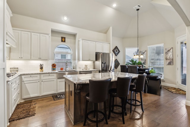 kitchen with a kitchen island, white cabinetry, lofted ceiling, sink, and stainless steel appliances