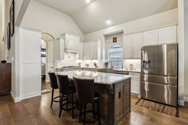 kitchen with lofted ceiling, appliances with stainless steel finishes, dark wood-style flooring, and custom range hood