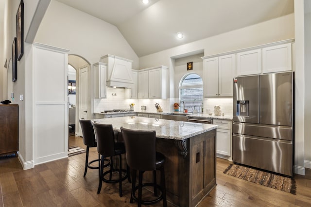 9916 Villa Verde Dr, Fort Worth, TX 76179 - kitchen featuring appliances with stainless steel finishes, custom range hood, vaulted ceiling, dark wood-type flooring, and light stone countertops