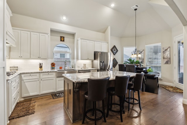 kitchen with dark wood-type flooring, vaulted ceiling, appliances with stainless steel finishes, white cabinetry, and a sink