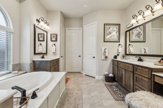 bathroom with a garden tub, two vanities, a sink, tile patterned flooring, and baseboards