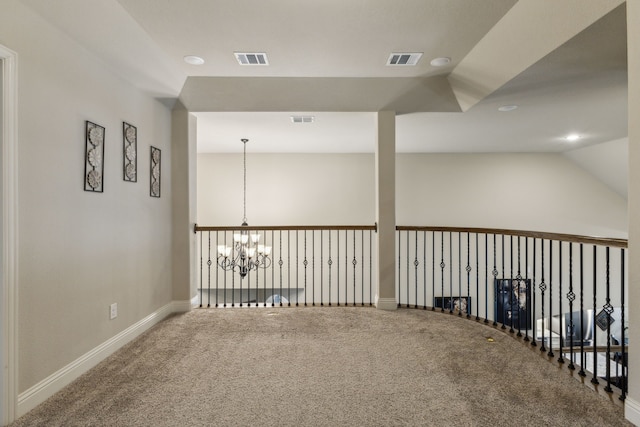 carpeted spare room featuring baseboards, visible vents, and a chandelier