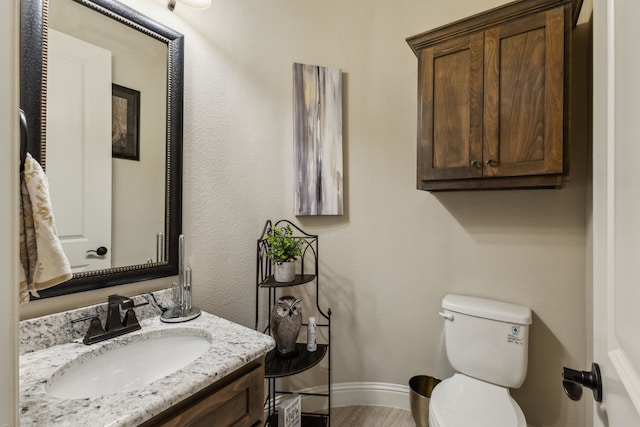 bathroom featuring vanity, toilet, wood finished floors, and baseboards