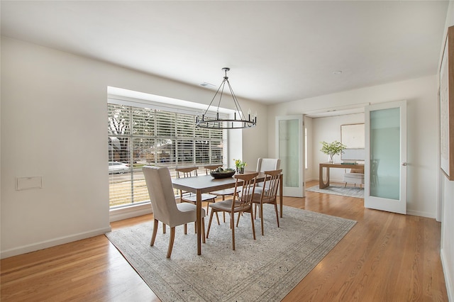 dining space with light hardwood / wood-style flooring and a notable chandelier