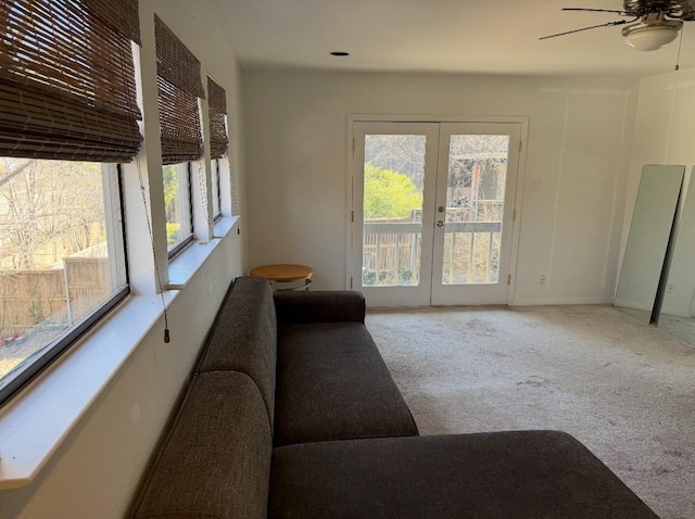 living area with a healthy amount of sunlight, ceiling fan, carpet flooring, and french doors