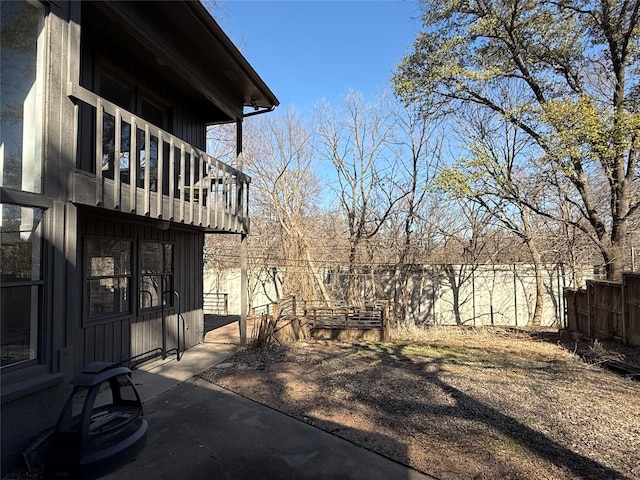 view of yard with a patio, fence, and a balcony