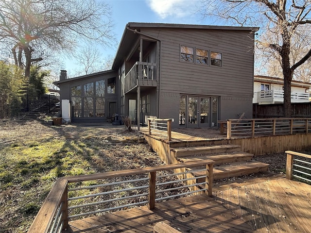 rear view of property with a balcony, brick siding, a deck, and french doors