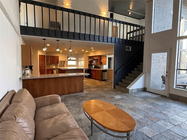 living area with a healthy amount of sunlight, stone tile floors, and stairs