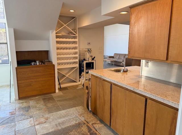 kitchen featuring tile counters, recessed lighting, stone finish floor, open floor plan, and a sink