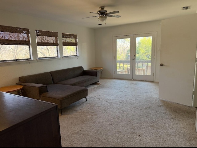 carpeted living room with visible vents, french doors, and a ceiling fan