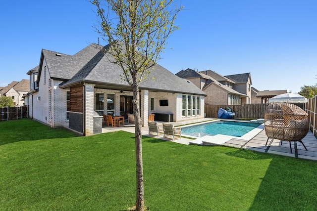 rear view of house with a fireplace, a fenced in pool, a patio area, and a lawn