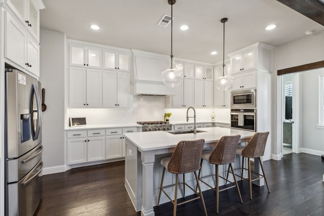 kitchen featuring a kitchen island with sink, sink, stainless steel appliances, and white cabinets