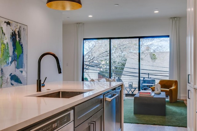 kitchen with light stone counters, dishwashing machine, and sink