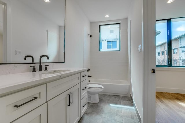 full bathroom featuring tiled shower / bath, vanity, and toilet