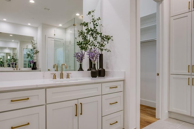 bathroom featuring walk in shower, vanity, and hardwood / wood-style flooring