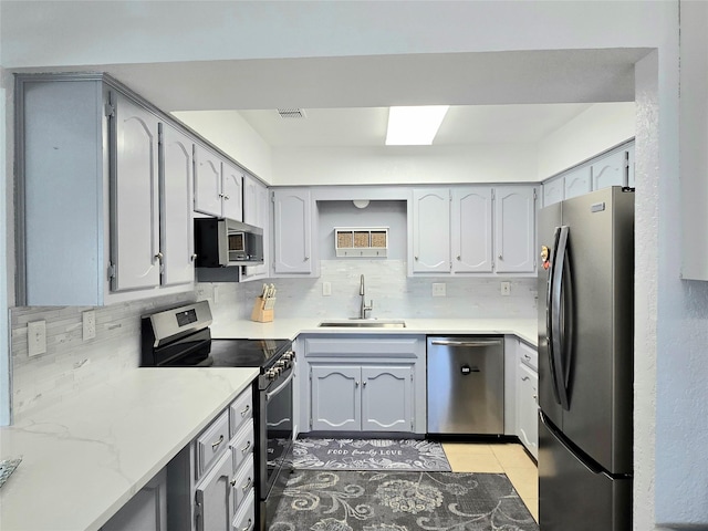 kitchen with sink, decorative backsplash, stainless steel appliances, and light tile patterned floors