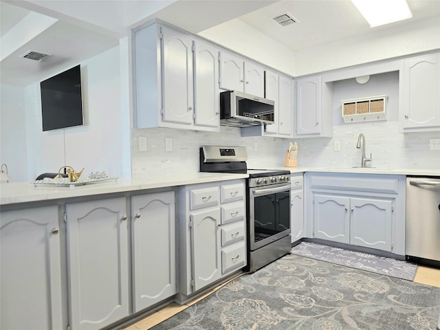 kitchen featuring appliances with stainless steel finishes, sink, gray cabinetry, and decorative backsplash