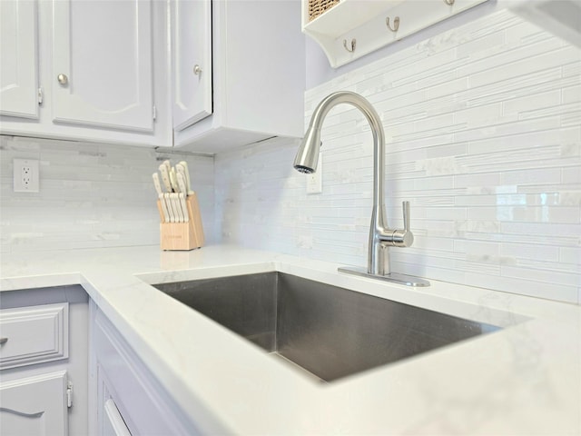 interior details featuring white cabinetry, sink, and backsplash