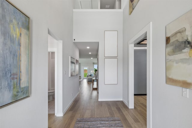 hall featuring a towering ceiling and light hardwood / wood-style floors