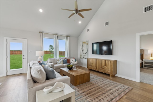 living room with light hardwood / wood-style flooring, high vaulted ceiling, and ceiling fan