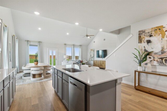 kitchen featuring dishwasher, sink, a center island with sink, and light wood-type flooring