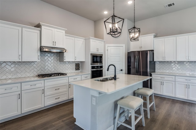 kitchen featuring a kitchen bar, sink, an island with sink, pendant lighting, and white cabinets