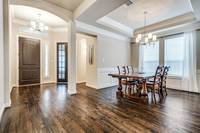 dining space with an inviting chandelier, a tray ceiling, dark wood-type flooring, and ornamental molding