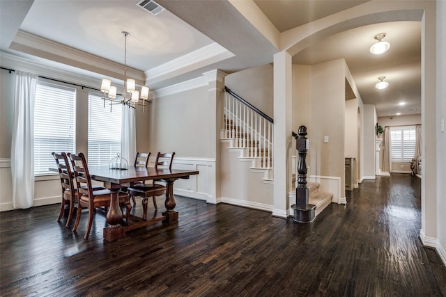 dining space featuring ornamental molding, dark hardwood / wood-style floors, a raised ceiling, and a notable chandelier