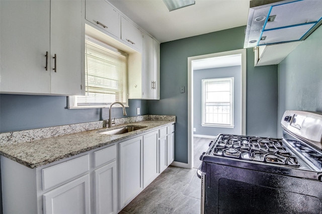 kitchen with white cabinetry, sink, light stone countertops, and gas range oven