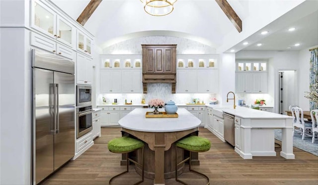 kitchen featuring white cabinetry, stainless steel appliances, a kitchen breakfast bar, and an island with sink