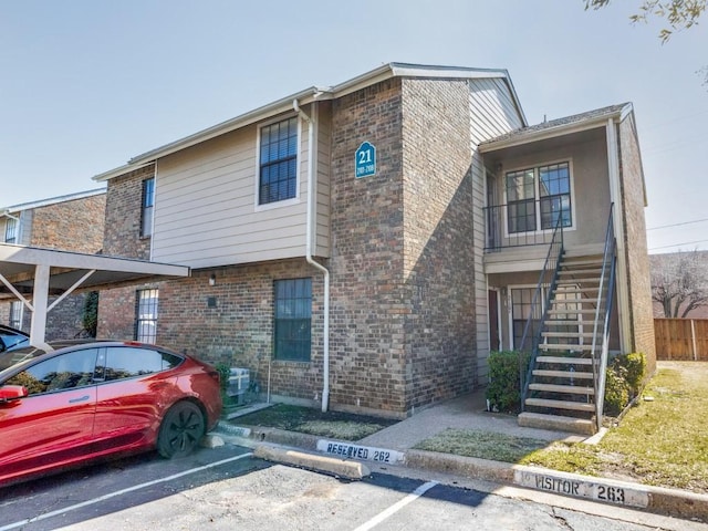 view of front of property featuring uncovered parking, stairway, and brick siding