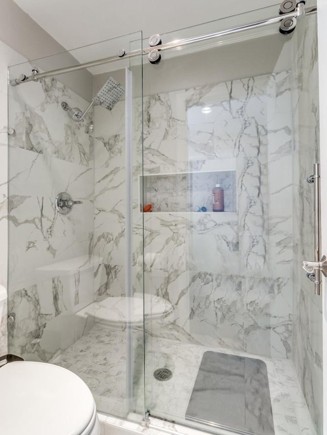 bathroom with a marble finish shower and toilet