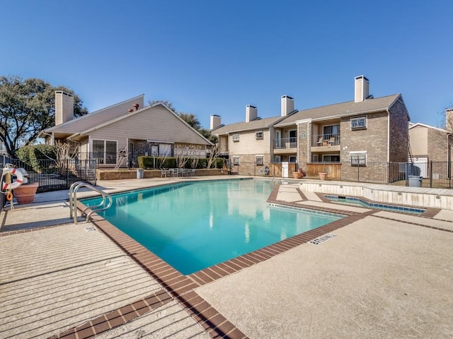 community pool with a patio area and fence