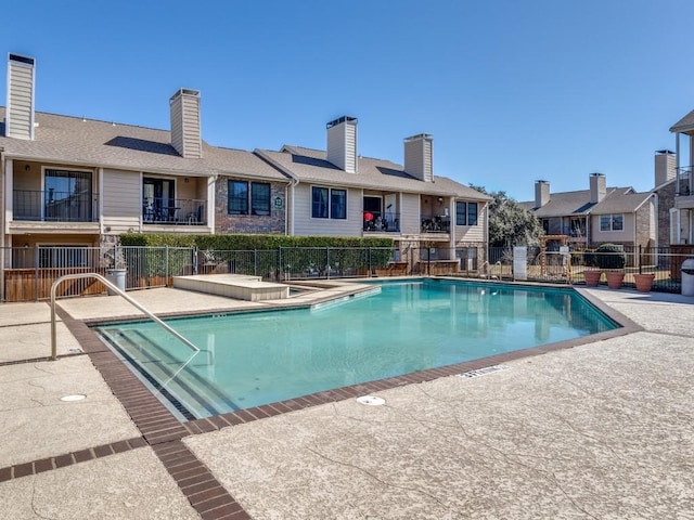 pool featuring a patio, fence, and a residential view