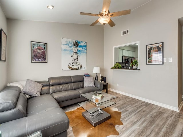 living area featuring visible vents, baseboards, a ceiling fan, lofted ceiling, and wood finished floors